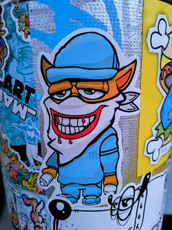 A sticker featuring a cartoon fox character with a large, toothy smile and dripping blood, wearing a blue cap and matching outfit. The art style is reminiscent of graffiti and street art. It is among various other stickers.