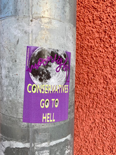 Street sticker A purple sticker with a picture of a full moon and the text "Moonlight Conservatives Go To Hell". The sticker is affixed to a metal pipe.