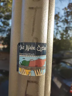 Street sticker A sticker featuring a stylized map of the Middle East and Asia, measured with a ruler by two hands.  The text "Der Nahe Osten" (The Middle East) is displayed prominently at the top, along with the Instagram handle "DesorientiertEuch". The design uses a simple, almost childlike aesthetic. 