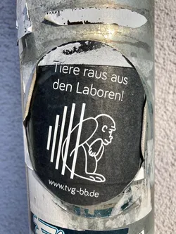 Street sticker A black and white sticker with a design depicting an ape sitting behind bars. The text on the sticker says 'Animals out of the labs!' in German and includes a website address.