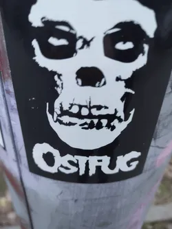 Street sticker Black and white sticker featuring a Misfits-inspired skull graphic with the word "OSTFUG" written beneath it.
