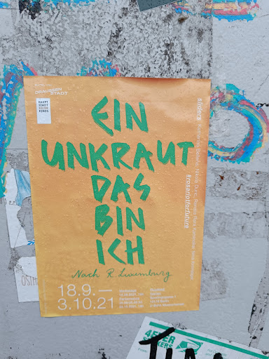 Street sticker A sticker featuring the text "Ein Unkraut das bin ich" (I am a weed) in green lettering on an orange background. It also includes dates (18.9. - 3.10.21), likely referring to an event or exhibition, and mentions  "Nach R. Luxemburg" (Following R. Luxemburg), suggesting a theme related to Rosa Luxemburg's philosophy.  The hashtag #rosariotforfuture is also visible.