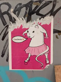Street sticker A rat, drawn in a simple style, is wearing a pink skirt and shoes. The rat has a matching purse. The background is bright pink. It has a speech bubble that says "I am Barbie" with a lipstick emoji.