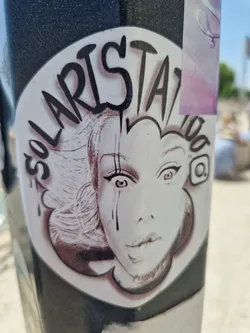 Street sticker A black and white illustration of a woman's face with tears, styled with graffiti-like text. The sticker features the text "Solaris Tattoo" and an Instagram logo.