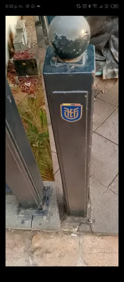 Street sticker The sticker is a shield-shaped emblem with a rounded bottom and a flat top. It features a prominent blue background with stylized golden-yellow letters 'UEF' centrally placed. Above the main blue body, there's a horizontal band displaying the yellow, blue, and red stripes of the Ecuadorian flag. The entire emblem is outlined in a thin golden-yellow border, giving it a clean and official appearance against the dark, weathered post.