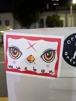 Rectangular sticker with a red border depicting a white face. Features large anime eyes with starry pupils, a pink forehead 'X', a smoking beak, and the text 'muebon' at the bottom.