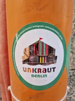 Round sticker with a green outer ring and white inner circle.  It features an illustration of a colorful structure and the text 'UNKRAUT BERLIN'.  Social media handles are printed on the sticker.