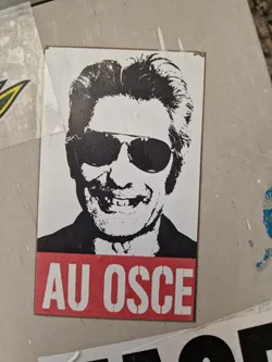 Street sticker Black and white sticker featuring a stylized portrait of a man wearing sunglasses.  The text 'AU OSCE' is displayed prominently at the bottom in red.