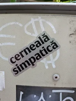 Street sticker A diagonal, die-cut sticker with a metallic silver background and bold black text reading 'cerneală simpatică' in Romanian.