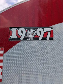 Street sticker A rectangular black and red sticker featuring the stylized white numbers '19' and '97' flanking a cartoon illustration of the snickering dog Muttley in the center.