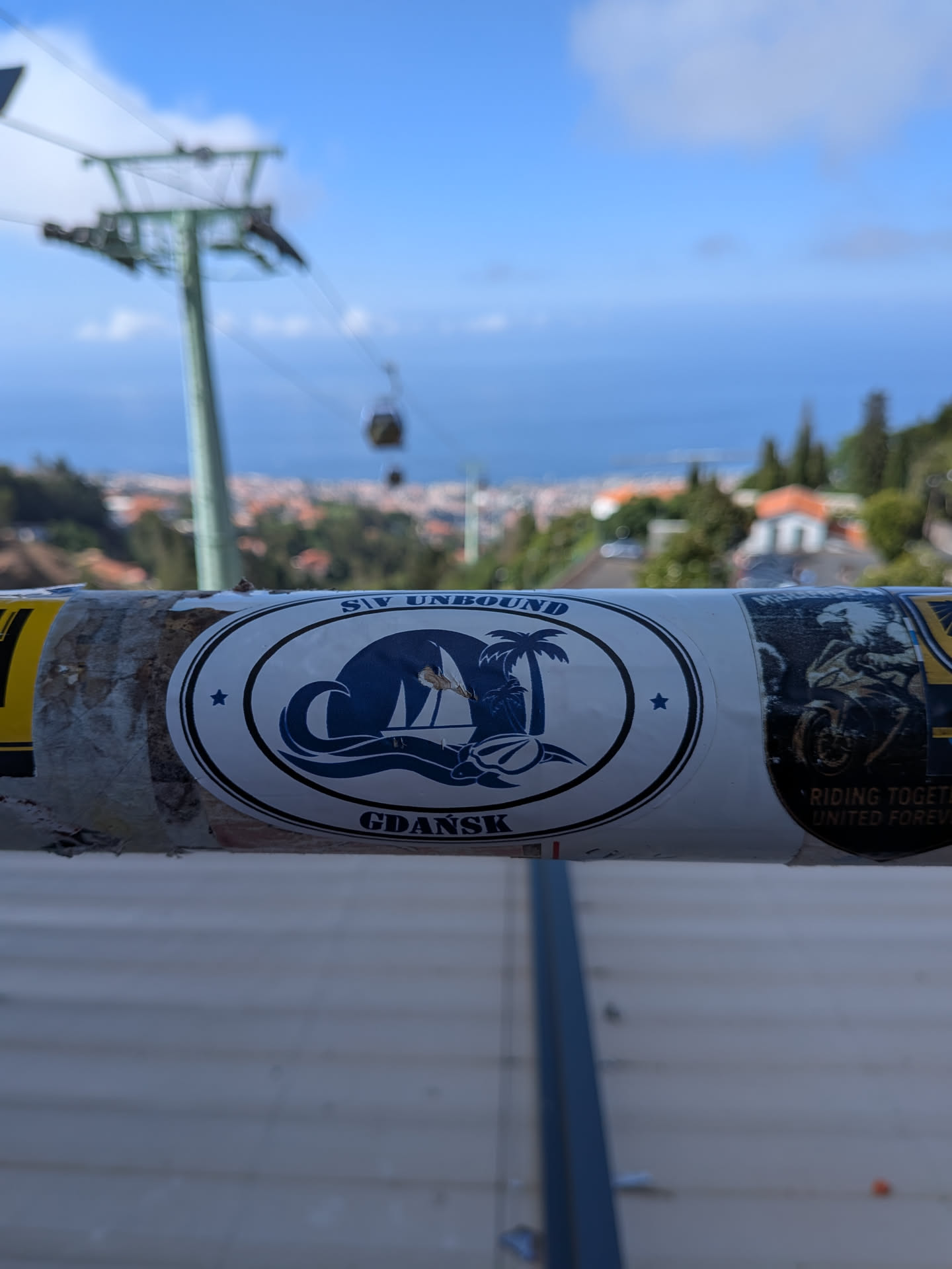 An oval white sticker with blue print. Features a sailboat on waves, a palm tree, and a sea turtle. Text reads 'S/Y UNBOUND' at the top and 'GDAŃSK' at the bottom, flanked by stars.