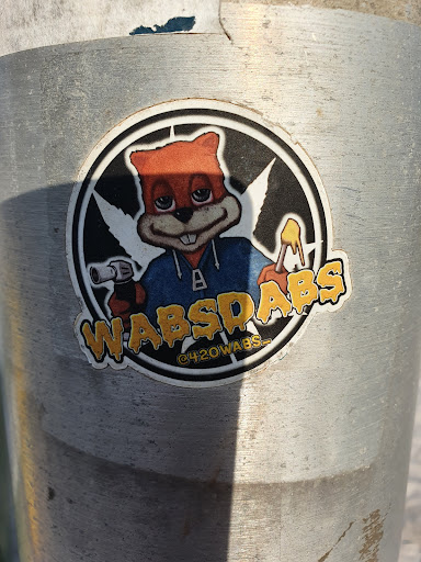 Street sticker A round sticker with a cartoon squirrel wearing a blue hoodie. The squirrel is holding a lighter and what seems to be a dab rig. The text "WABSDABS" is written in a dripping style, and "@420WABS" is written smaller underneath. The background is black with a marijuana leaf design.