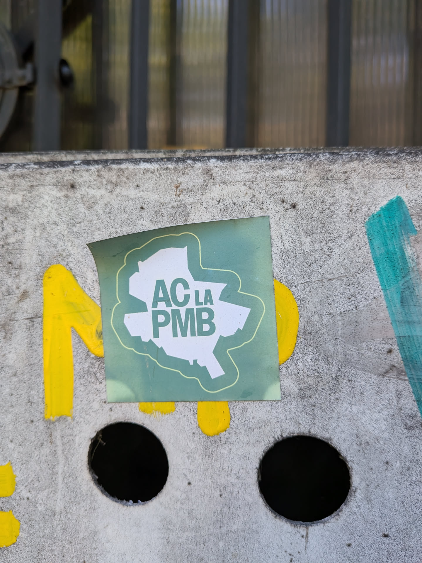A square sticker with a faded green background, showing a white silhouette map of Bucharest. The text 'AC LA PMB' is printed in green inside the map shape.