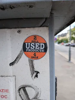 Street sticker A round sticker divided into three horizontal sections. The top and bottom sections are orange with black text reading '2 SELL' and '4 SALE'. The middle section is a black band containing the white text 'USED PRODUCTS'.