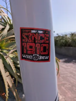 Street sticker Rectangular sticker on a white pole. Features distressed red text 'SINCE 1910' on a black background, with the white text 'WIDZEW' and the club's circular crest at the bottom.