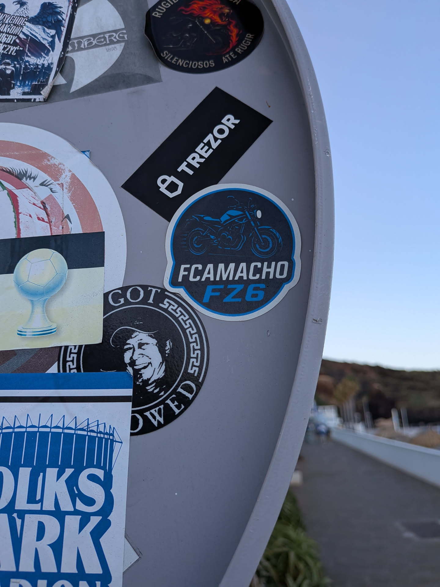 A circular sticker with a black background, a blue border, and a blue motorcycle silhouette. Below the graphic, 'FCAMACHO' is written in white sans-serif font, and 'FZ6' is written in bold blue font.