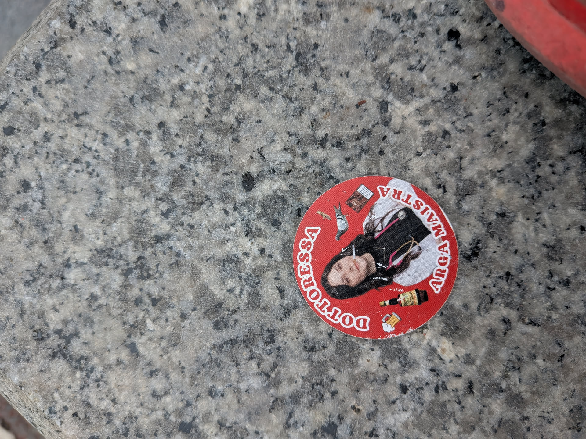 Circular red sticker showing a woman in a doctor's coat with a stethoscope and cigarette. Surrounding icons include a pigeon, beer, and cigarettes. White text reads 'DOTTORESSA ARGA MAISTRA'.