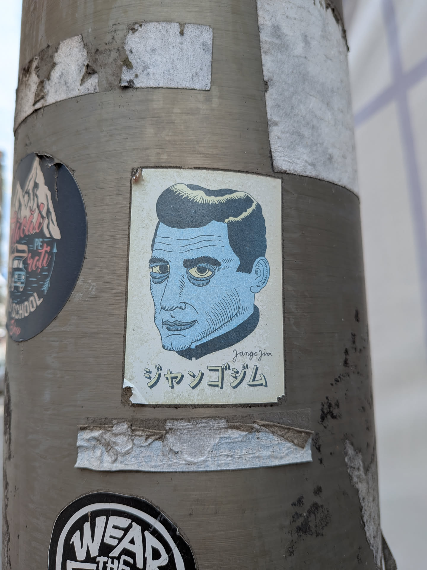 Rectangular sticker depicting a blue-skinned man with a pompadour and tired, yellow-rimmed eyes. Features the signature 'Jangojim' and Japanese katakana 'ジャンゴジム' on an off-white background.