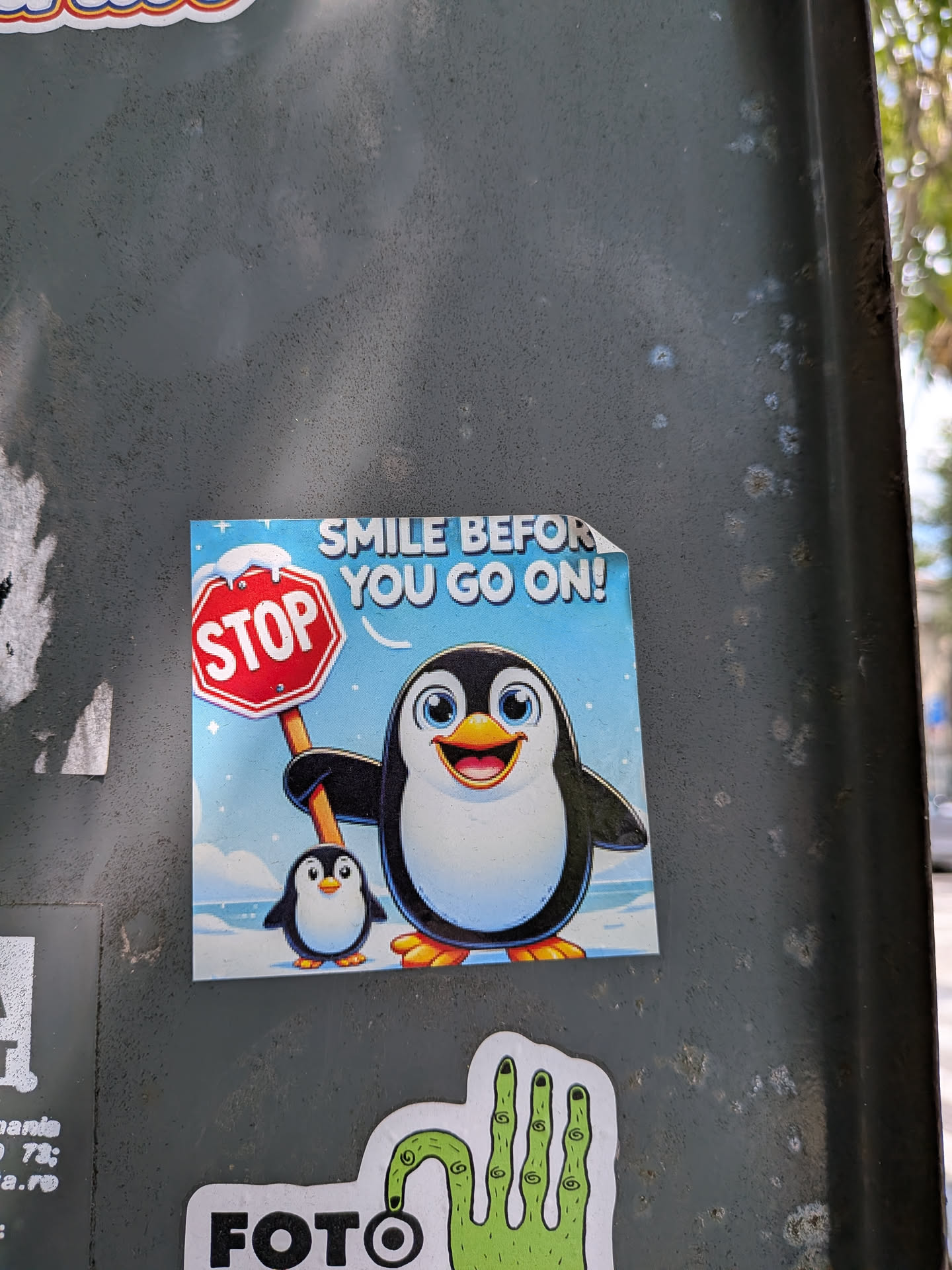 Square sticker featuring a cheerful cartoon penguin holding a snow-capped 'STOP' sign next to a smaller penguin. Set against a snowy blue background with the text 'SMILE BEFORE YOU GO ON!'.
