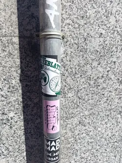 Street sticker The sticker is a vertical pink rectangle featuring stylized white text with black outlines. On the left, small black text reads "*SPNZ*". The prominent central text, rendered in a graffiti bubble-letter style, appears to spell "Chills," with the initial 'C' resembling a cartoon hand or character and the final 's' also highly stylized. A small black abstract symbol is visible on the right side.