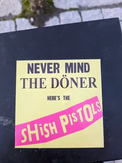 Street sticker A sticker parodying the Sex Pistols' album cover.  It replaces "Never Mind the Bollocks" with "Never Mind the Döner" and features a pink banner reading "Shish Pistols".