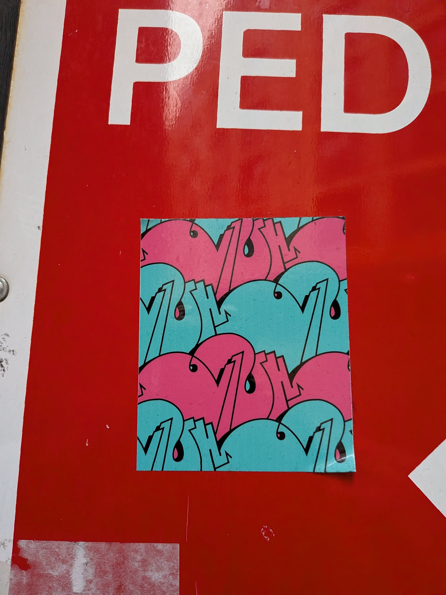 A square sticker featuring a dense, repeating pattern of stylized, rounded shapes, reminiscent of bubble letters or graffiti tags. The primary colors are bright pink and a light teal/aqua blue, with all shapes outlined in black. Several elements within the pattern include small black 'drips' or teardrop shapes, adding to the graffiti aesthetic. The pattern fills the entire sticker, creating a continuous and dynamic design. The sticker is placed on a glossy red surface.