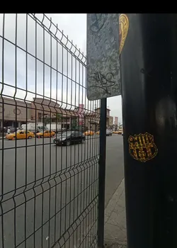 Street sticker A shield-shaped sticker, predominantly gold and black, affixed to a black pole. The top section features vertical stripes. In the center, the black letters 'B.S.C.' are clearly visible. Below the letters, a stylized football (soccer ball) is depicted. The sticker has a slightly metallic or foil appearance and shows minor signs of wear and tear, suggesting it's an authentic outdoor application.