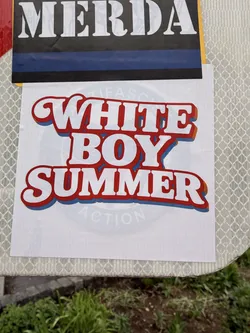 Street sticker The sticker is a white rectangular decal featuring the phrase "WHITE BOY SUMMER" stacked in three lines. The text is rendered in a prominent, rounded, sans-serif font with a distinct retro or vintage style. Each letter is white, outlined in a thick red, followed by a thinner orange drop shadow, and a final blue drop shadow, creating a vibrant, multi-layered, and three-dimensional effect. Faintly visible in the background, beneath the main text, is a light blue circular graphic with some barely legible text, which appears to be 'ANTIFA' and 'ACTION', but it is largely obscured and faded.