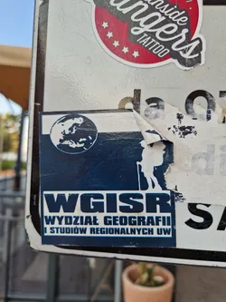 Street sticker A dark blue sticker with a world map, silhouettes of hikers, and the acronym WGISR, which stands for Wydział Geografii i Studiów Regionalnych UW (Faculty of Geography and Regional Studies, University of Warsaw).
