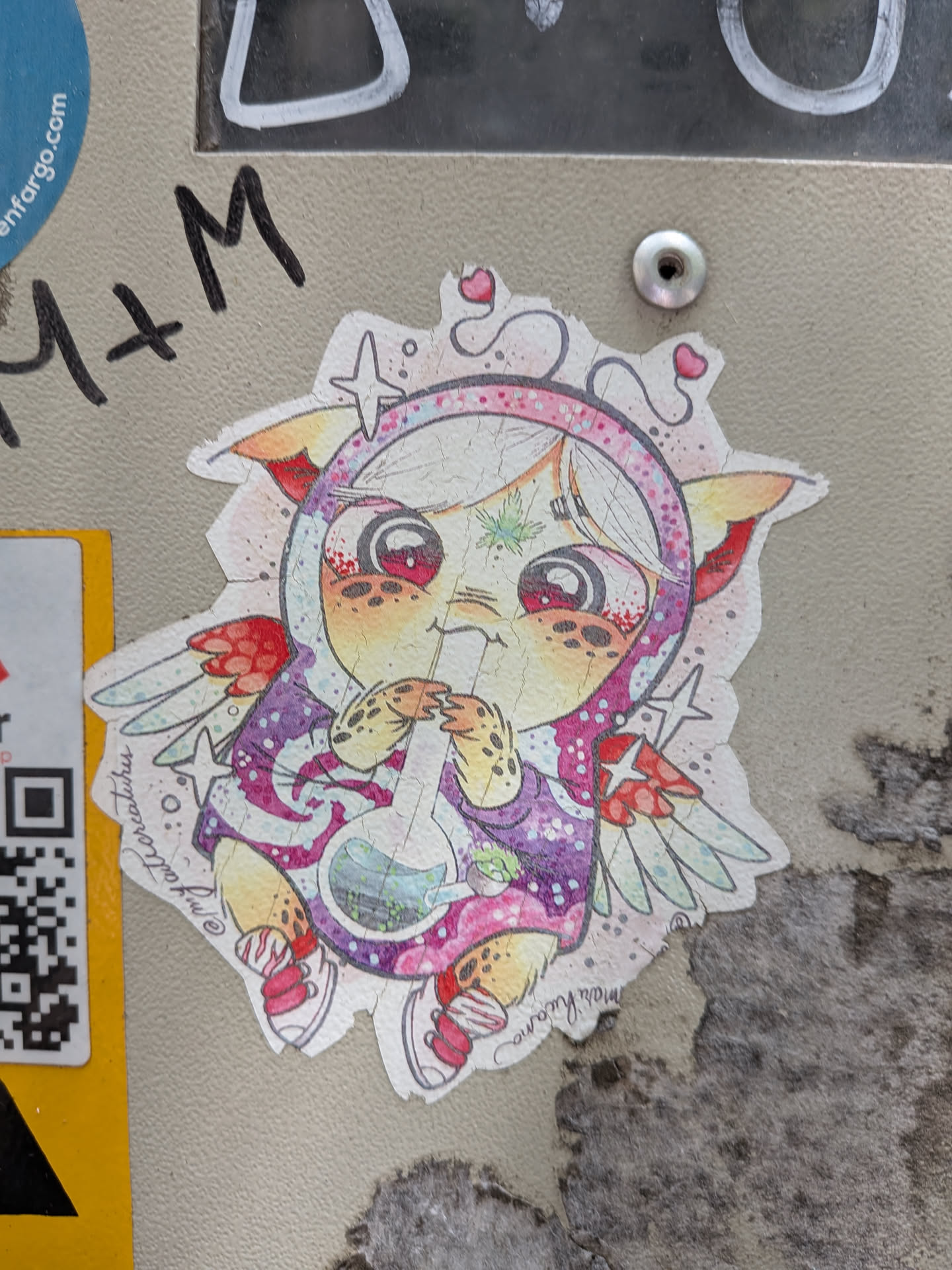 A die-cut sticker depicting a cute, winged anime-style creature with large red eyes, wearing a purple patterned hoodie and using a glass bong. It features a green cannabis leaf on its forehead, surrounded by stars and hearts.