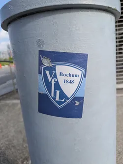 Street sticker A rectangular blue sticker displaying the shield emblem of German football club VfL Bochum 1848. The shield is split diagonally into blue and white sections with corresponding text. The sticker shows slight peeling and wear.