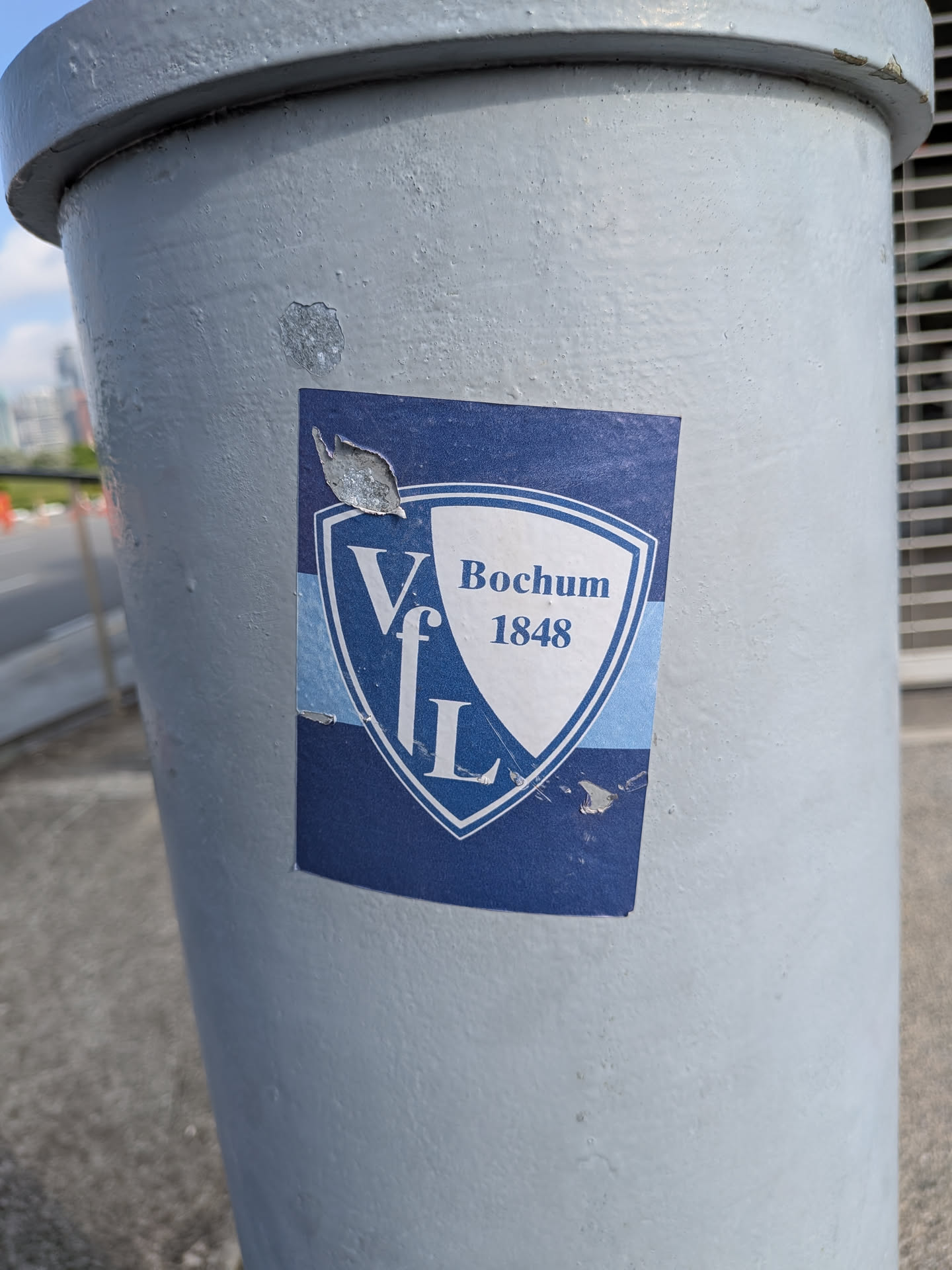 A rectangular blue sticker displaying the shield emblem of German football club VfL Bochum 1848. The shield is split diagonally into blue and white sections with corresponding text. The sticker shows slight peeling and wear.