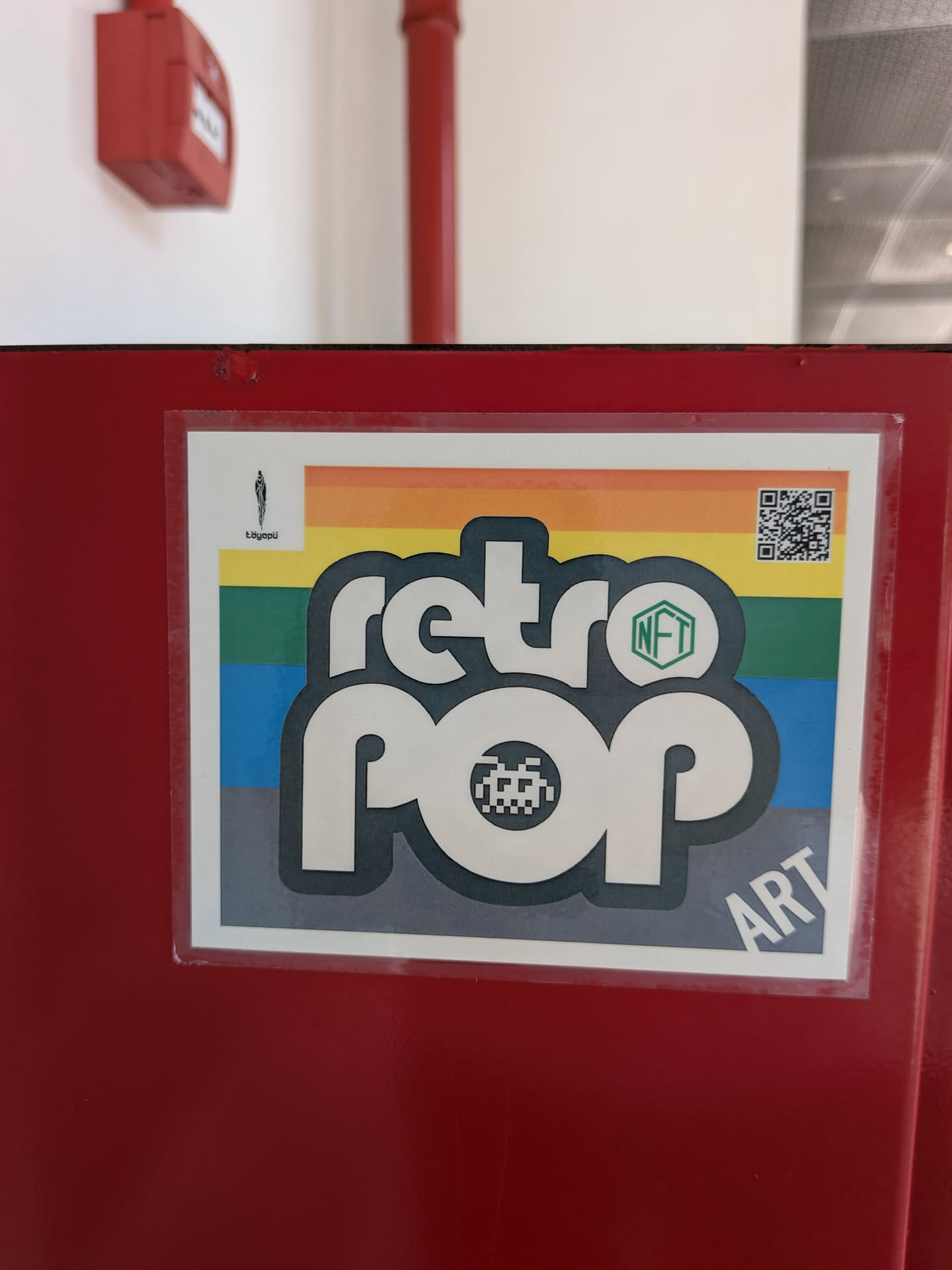 A rectangular sticker featuring the stylized text 'retro pop' in white with a dark outline. The background consists of horizontal rainbow stripes. It includes a pixelated alien icon, a green 'NFT' hexagon, a QR code in the top right, and 'töyopü' branding in the top left.