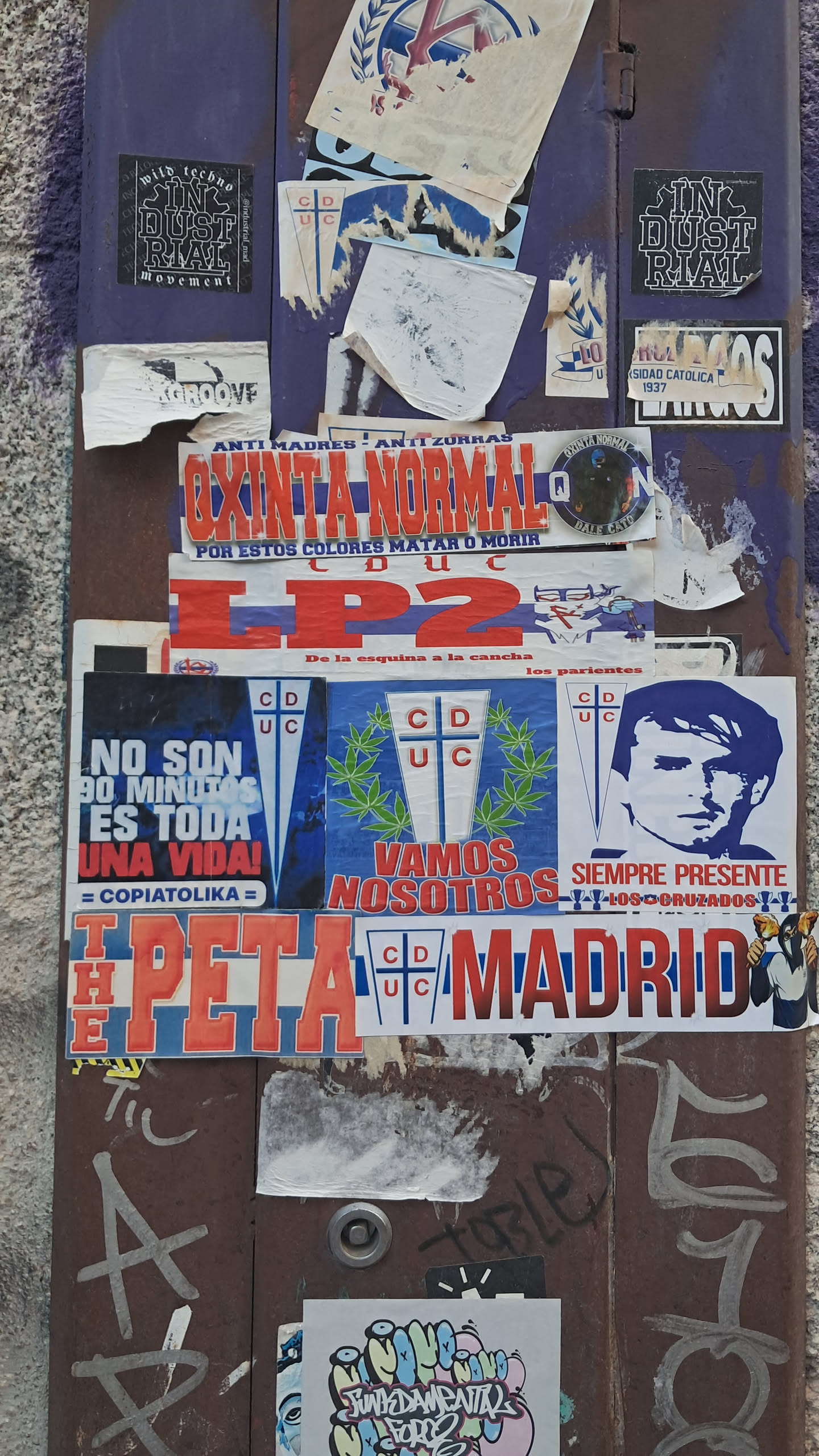 A rectangular sticker featuring large, bold red block letters 'LP2' prominently displayed on a white background. Below the main 'LP2' text, in smaller blue lettering, it reads 'De la esquina a la cancha los parientes'. To the left of this smaller text, there is a small, partially obscured blue and white crest or logo, which appears to be a stylized 'CDUC' emblem. The sticker shows signs of wear, including minor discoloration and slight peeling at its edges, indicating its physical presence on a textured, weathered surface.