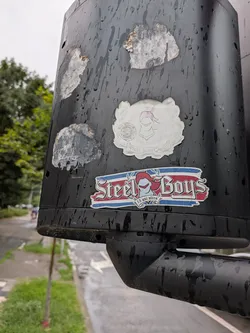 Street sticker A faded, die-cut white sticker featuring a central knight's helmet crest. It includes a circular emblem on the left and a banner at the bottom reading 'STEEL BOYS GALATI' flanked by the year '2006'.
