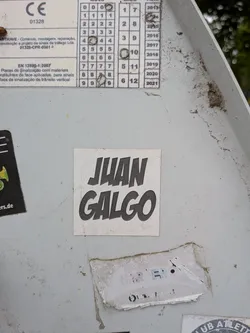 Street sticker A square white sticker featuring the name 'JUAN GALGO' in bold, stylized black lettering with a slight slant, affixed to a grey metal surface.