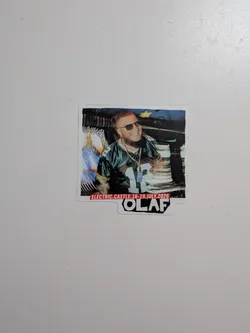 Street sticker Die-cut sticker featuring a photo of a bearded man in sunglasses and a Green Bay Packers jersey. A red banner at the bottom reads 'ELECTRIC.CASTLE.16-19.JULY.2026', with 'OLAF' printed in bold black text below.