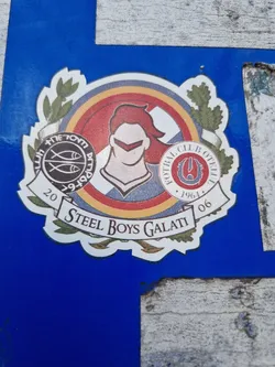 Street sticker Round sticker featuring a logo with a stylized figure in the center, surrounded by laurel wreaths and other design elements. The text 'Steel Boys Galati' is clearly visible at the bottom.  The logo also includes the years 20 and 06, and what appears to be a football club emblem.