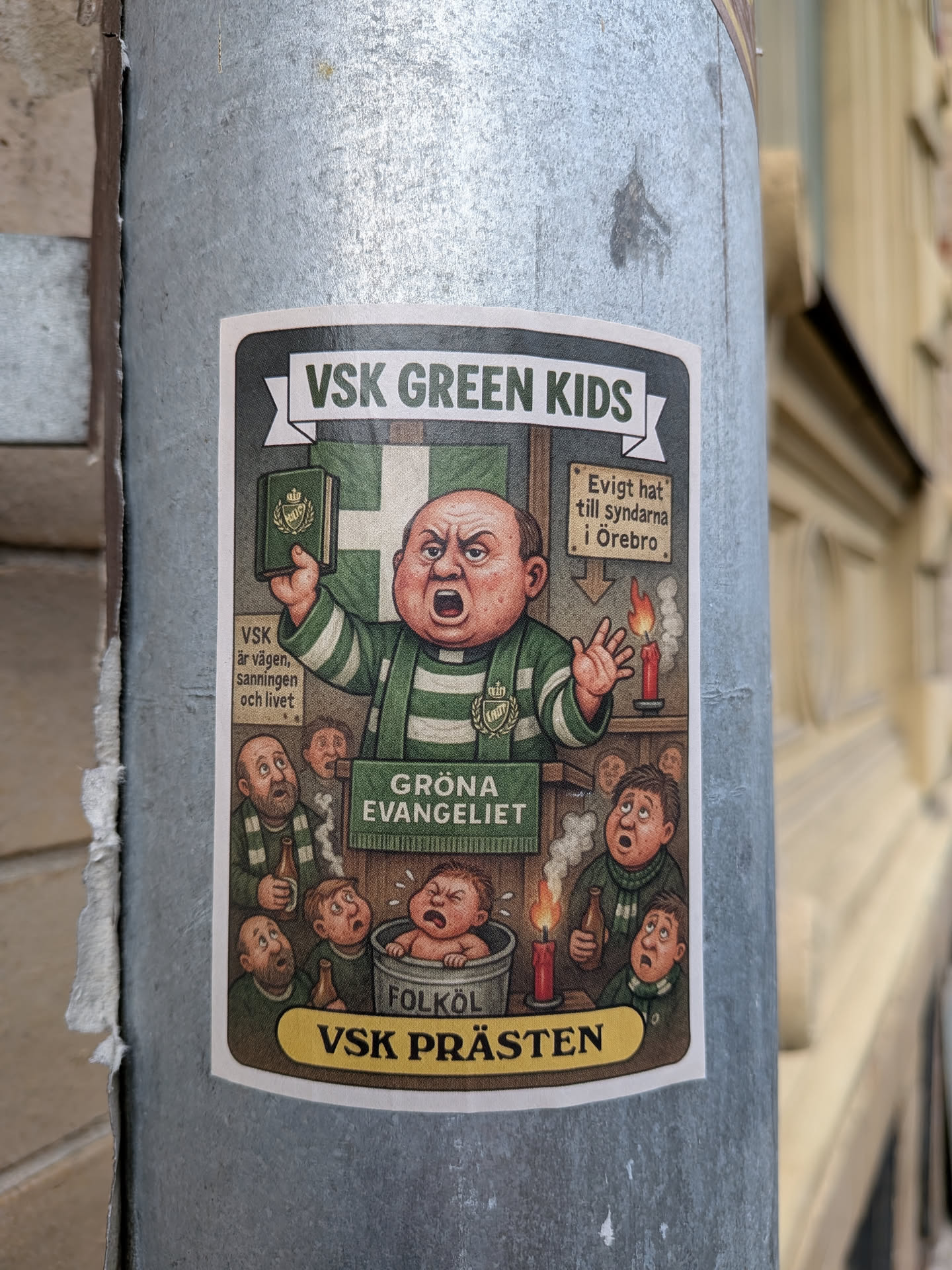 The sticker features a caricature of a portly, angry preacher in a green and white striped robe, holding up a green book with a crown emblem. He stands before a crowd of men with exaggerated expressions of shock and confusion. In the foreground, a baby is depicted in a tub labeled 'FOLKÖL' (meaning 'people's beer'). Behind the preacher, a candle burns, and a sign reads 'Evigt hat till syndarna i Örebro' (Eternal hate to the sinners in Örebro). The background includes a green and white checkered flag, possibly representing a sports team. The overall style is cartoonish and satirical, with a limited color palette dominated by greens, reds, and skin tones.
