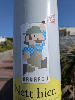 Street sticker A rectangular sticker depicting an 8-bit Mario character wearing a green hat, blue checkered shirt, and brown lederhosen. The text 'BAVARIO' is written below in a pixelated font.
