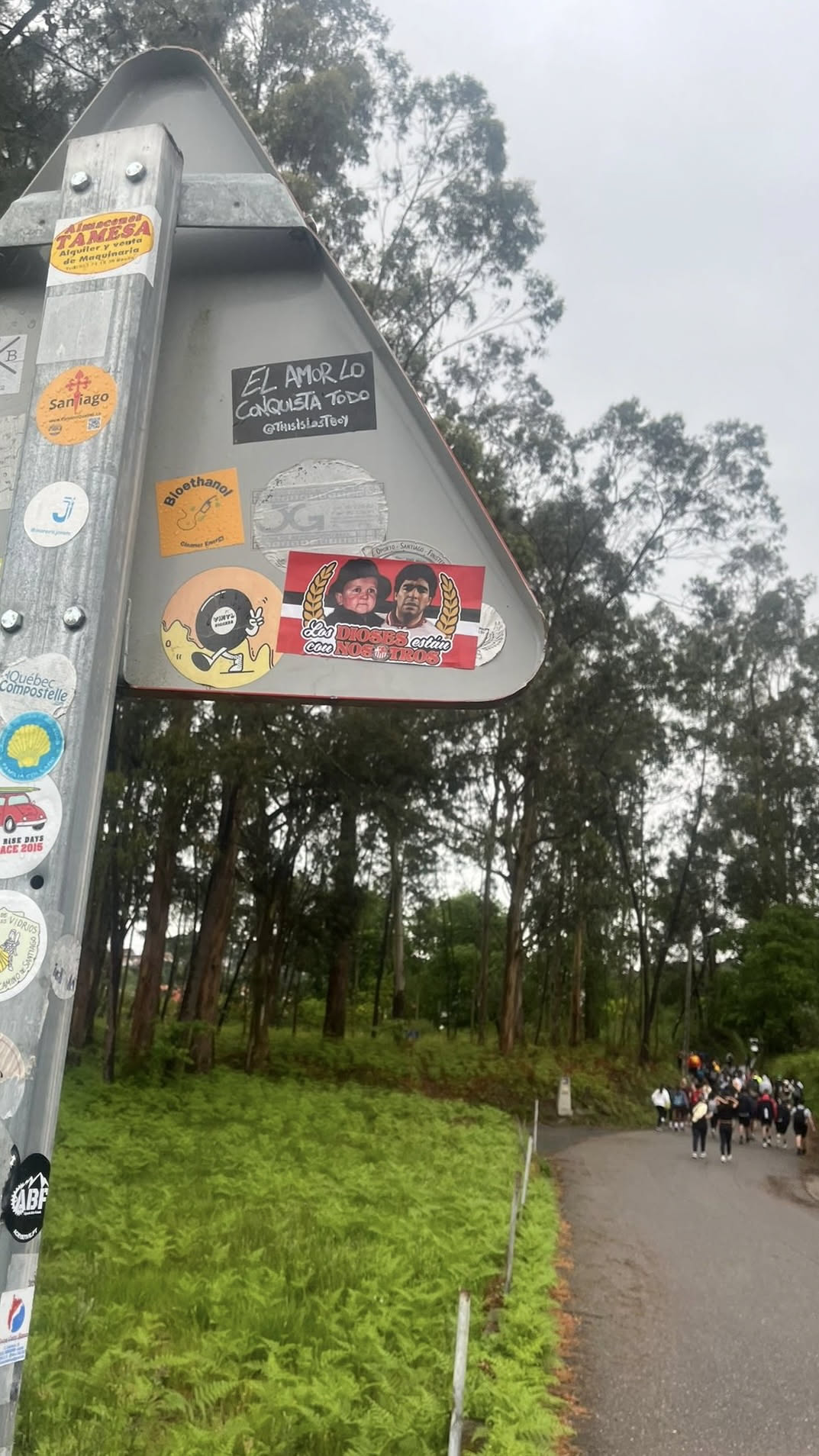 A rectangular sticker featuring a red and white striped background, reminiscent of the Argentine flag. On the left, it depicts Hasbulla Magomedov, and on the right, Diego Maradona, both from the chest up. The figures are framed by golden laurel wreaths on either side. Below them, white text with a red outline reads 'Los DIOSES están con NOSOTROS'.