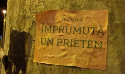 Street sticker A sticker on a pole with text in Romanian that says "Try borrowing a friend."  The bottom shows a website address that is partially visible.