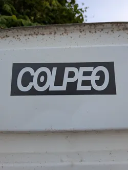 A rectangular black sticker featuring the word 'COLPEO' in bold white sans-serif font. The letters are closely kerned, and the final 'O' contains a horizontal line through the middle.