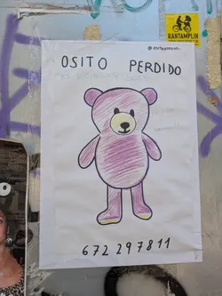 Street sticker This is a hand-drawn poster featuring a pink teddy bear. Above the drawing, the text reads "Osito Perdido" which translates to "Lost Teddy Bear". Underneath it says "es vicioso y sucio" which means "he is addicted and dirty". There is also a phone number written at the bottom, 672 297811.  Someone has added the text "Ku esgay macnavita" next to the teddy. At the top, the Instagram handle @ositoperdido_ is visible.