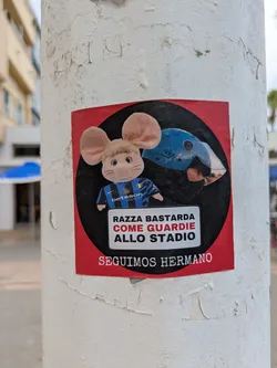 Street sticker The sticker is red and black. The mouse is wearing an Inter Milan jersey with the Betsson Sport logo. Text on the sticker reads 'RAZZA BASTARDA COME GUARDIE ALLO STADIO SEGUIMOS HERMANO'.