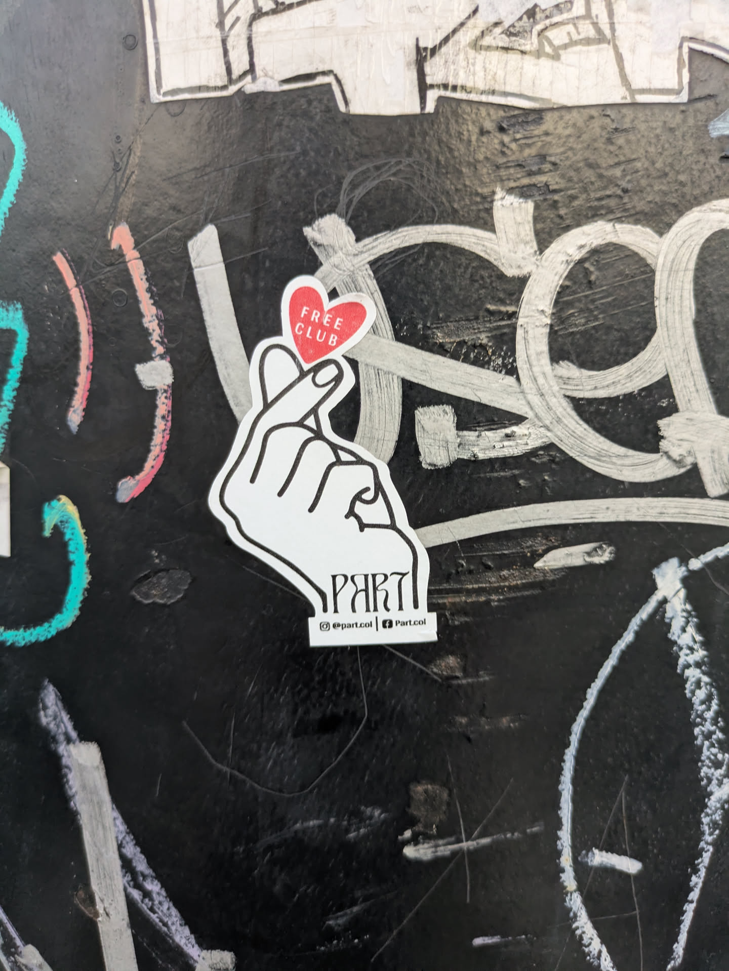 Street sticker A white sticker showing a finger heart with a red heart shape above the fingers, containing the text "Free Club". Below the hand is the word "Part". The sticker also includes links to @part.col on Instagram and Part.col on Facebook.