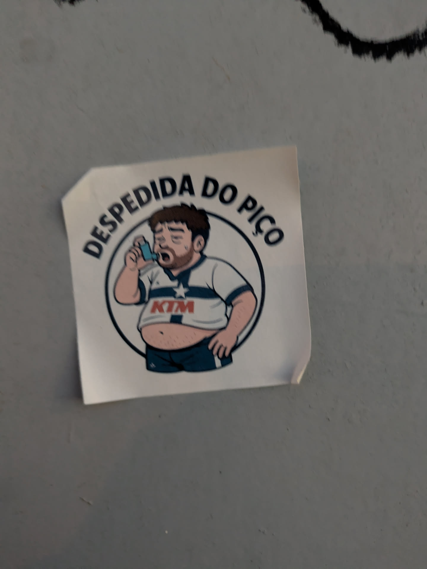 A sticker depicts a cartoon man with a slightly overweight build, wearing a sports shirt with 'KTM' emblazoned on it. He's using an inhaler and encircled by the text 'DESPEDIDA DO PIÇO'.