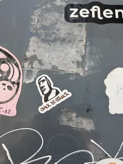 Street sticker A die-cut sticker featuring a black and white graphic of a Moai statue head. Below the head, the Romanian text 'OMUL DE STÂNCĂ' is written in a stylized, brown-outlined font.
