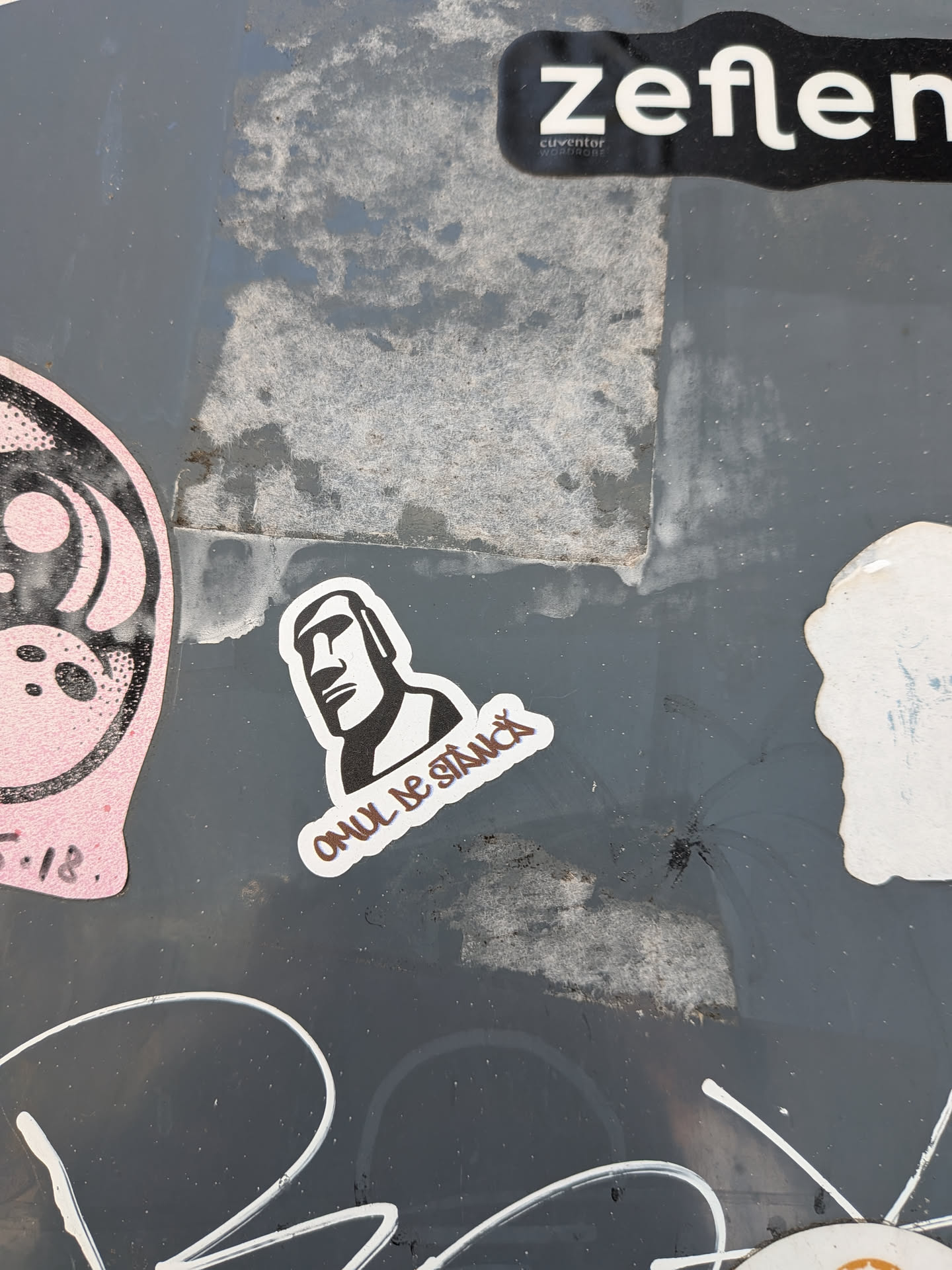 A die-cut sticker featuring a black and white graphic of a Moai statue head. Below the head, the Romanian text 'OMUL DE STÂNCĂ' is written in a stylized, brown-outlined font.