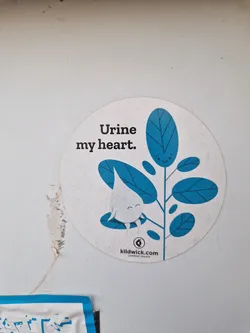 Street sticker Round sticker with a cute illustration of a drop of urine under a leaf, with the text "Urine my heart."  The sticker also includes a website address.